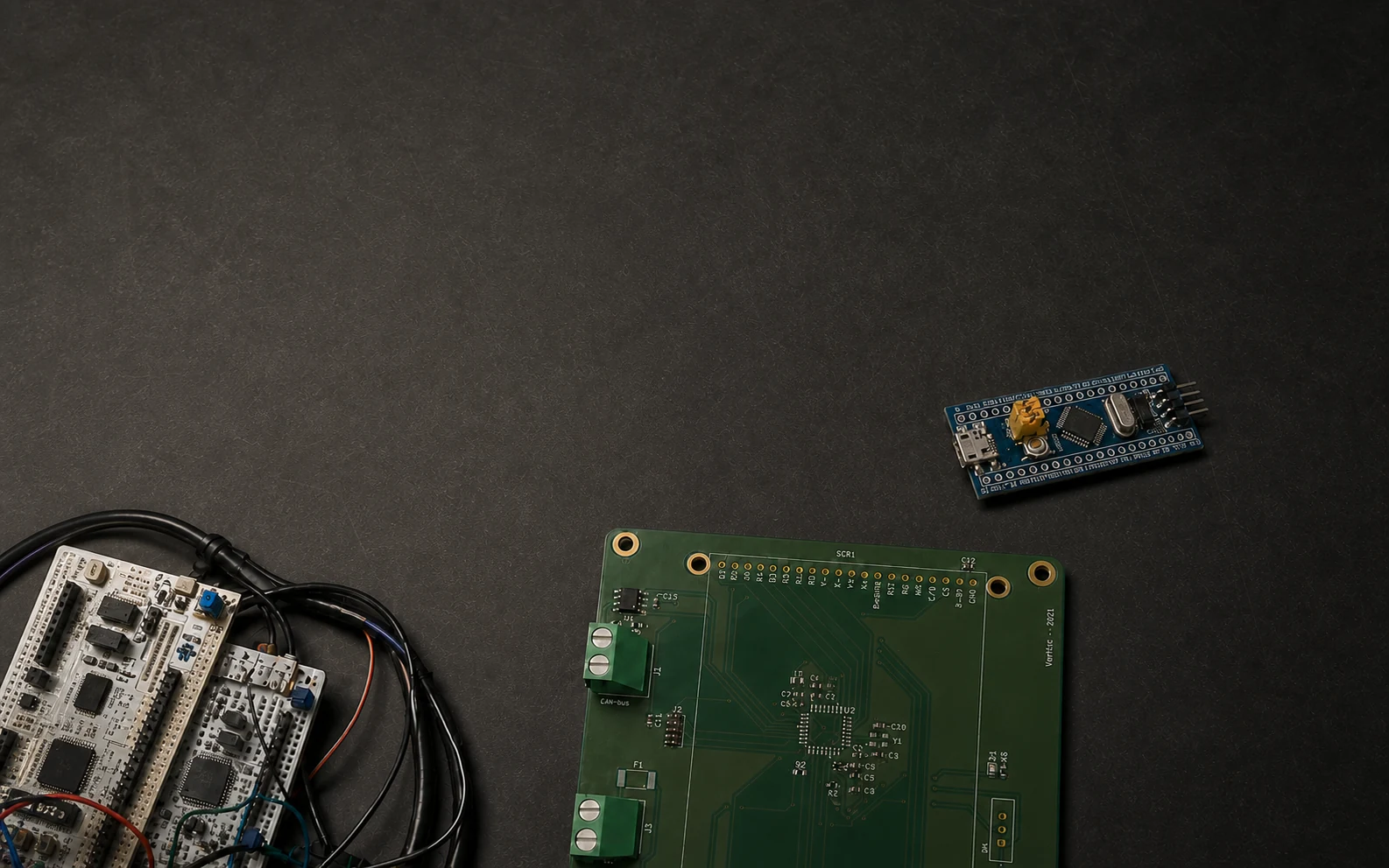 Placas STM32, PCB de estado vehicular y prototipo de presión organizados sobre una mesa de grafito